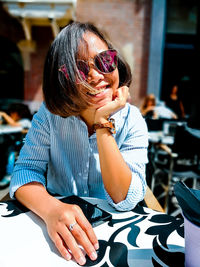 Portrait of smiling woman wearing sunglasses while sitting at cafe