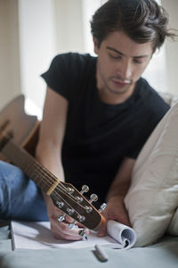 Young musician writing songs on an acoustic guitar