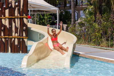 Smiling girl on slide in swimming pool