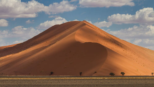 Scenic view of desert against cloudy sky