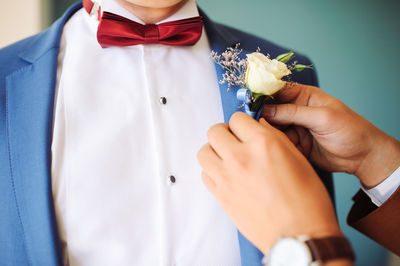Friend assisting bridegroom while wearing boutonniere during wedding