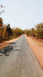 Road amidst trees against clear sky