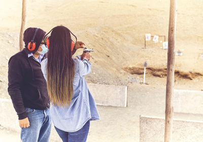 Woman releasing stress, instructor helping woman with gun