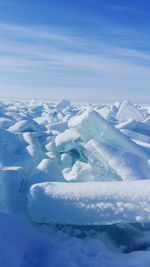 Aerial view of snow covered landscape against blue sky