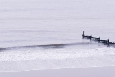 Scenic view of snow covered land and sea against sky