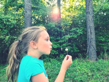 Side view of young girl blowing a dandelion