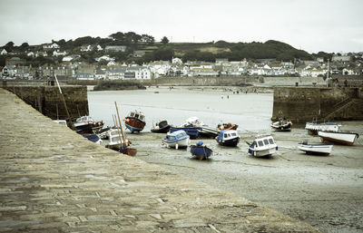 Boats moored at harbor against sky
