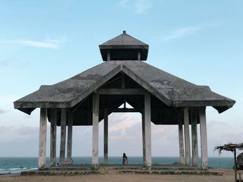 Rear view of lifeguard hut on beach against sky