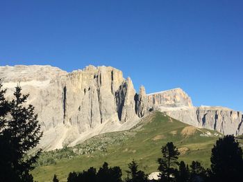 Low angle view of rocky mountains against clear blue sky