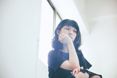 Portrait of young woman against wall