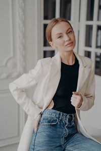 Portrait of young woman standing against wall