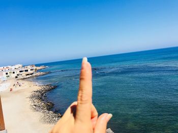 Midsection of person on sea against clear sky