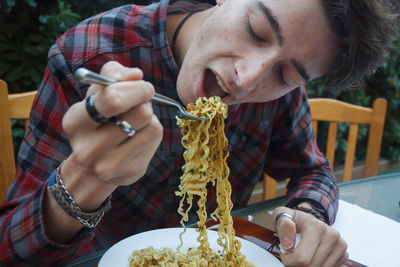 Close-up of man eating noodles at table