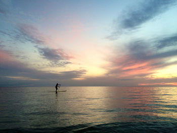 Silhouette person in sea against sky during sunset