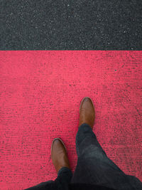 Low section of man standing on red road