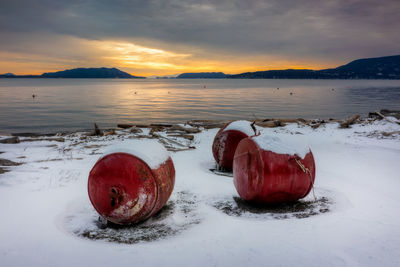 Fishing buoys covered with snow at sunset. 