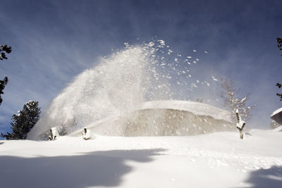 Low angle view of snow falling against sky