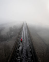 Aerial landscape of railway tracks vanishing into distance with a suicidal person walking in despair