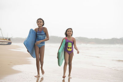 Full length portrait of friends on beach against sky