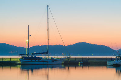 Sailboats in sea at sunset