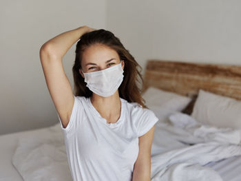 Young woman sitting on bed at home