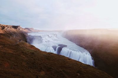 Scenic view of waterfall on mountain against sky