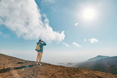 Rear view of man standing on mountain against sky