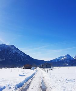 Scenic view of snow covered mountains against blue sky