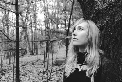 Portrait of young woman standing by bare tree