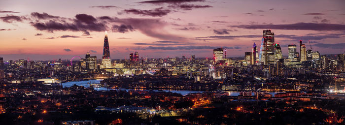 Illuminated cityscape against sky during sunset