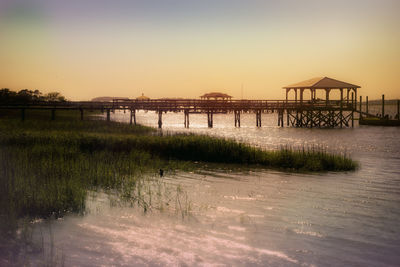 Pier over sea against sky during sunset