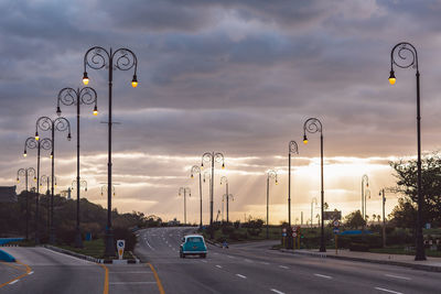 Vehicles on road against cloudy sky