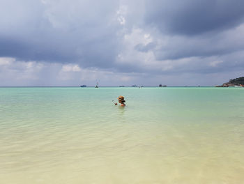 Boat sailing in sea against cloudy sky