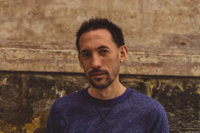 Portrait of young man standing against wall