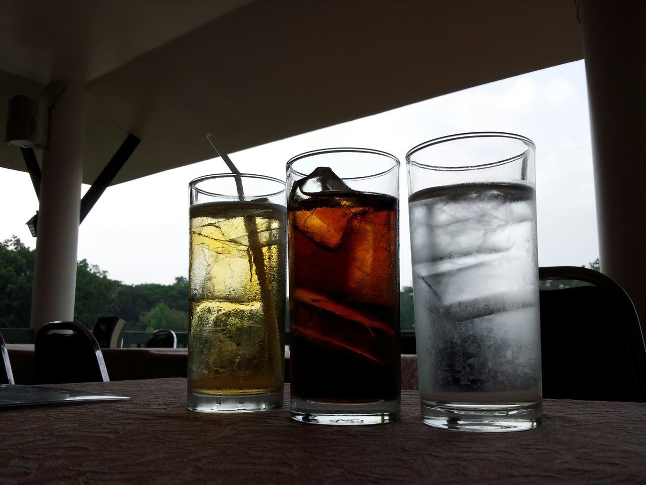 indoors, glass - material, window, transparent, table, glass, drink, food and drink, chair, absence, drinking glass, day, sunlight, reflection, empty, sky, refreshment, no people, home interior, tree