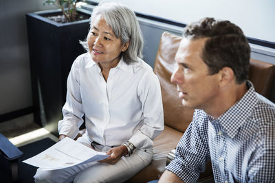 Businesswoman holding document while sitting with colleague in meeting room