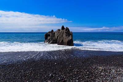 Rocks on sea shore against sky