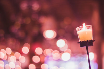 Close-up of illuminated candles on glass