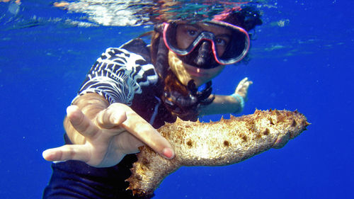 Woman holding fish while swimming in sea