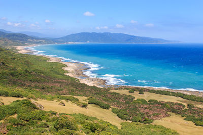 Scenic view of landscape by sea against sky