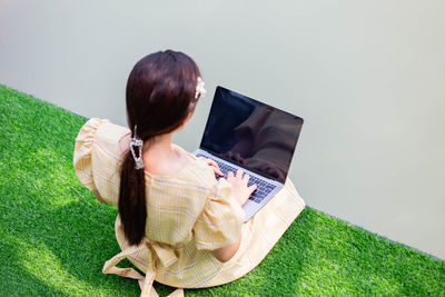 Woman using mobile phone while sitting on grass