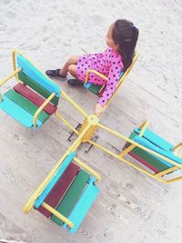 High angle view of girl sitting on merry-go-round in park