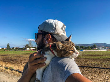 Man with cat on field against clear sky