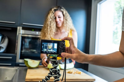 Cropped hand filming woman preparing food