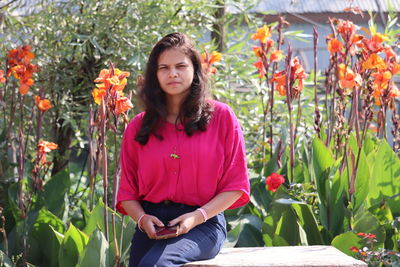 Portrait of young woman sitting amidst plants