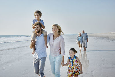 Happy extended family strolling on the beach