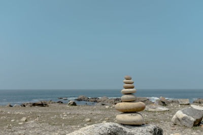 Stack of pebbles on beach against clear sky