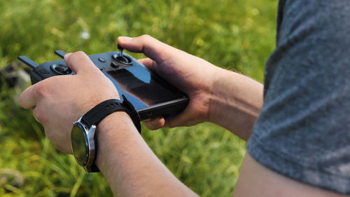 Close-up of the hands of a male drone operator operating a quadcopter in nature. 