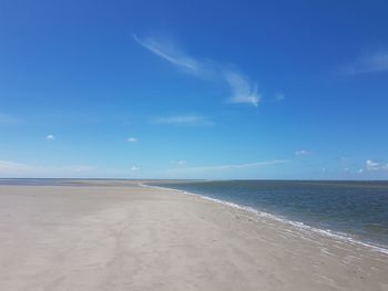 Scenic view of beach against blue sky