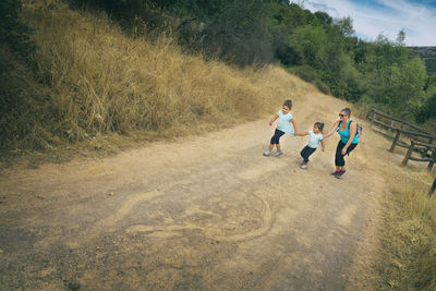 Smiling mature woman playing with daughters on road at forest